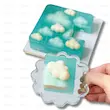 قالب سیلیکونی ابر در دست کاربر هنگام جدا کردن ژله فانتزی آبی با طرح ابرهای شناور روی سطح دسر