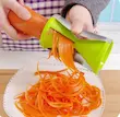 تراش سبزیجات دو کاره مشکی بلوکیش در حال رشته کردن هویج تازه روی بشقاب سفید، نمایش عملکرد سریع و دقیق تیغه مارپیچ.