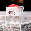 لیوان شیشه‌ای دوجداره مکعبی با ژله زرد و لایه خامه‌ای تزئین‌شده با گلبرگ خشک