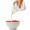 لیوان شیشه‌ای دوجداره طرح پاکت شیر حاوی شیر فوم‌دار، قرار گرفته روی میز صبحانه