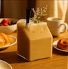 لیوان‌های شیشه‌ای طرح پاکت شیر در حال ریختن شیر روی صبحانه با توت تازه