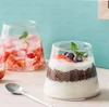 دو لیوان شیشه‌ای مدرن مخروطی با دسر شکلاتی و لایه خامه‌ای، تزئین‌شده با توت‌فرنگی تازه و برگ نعنا