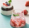 لیوان شیشه‌ای مدرن مخروطی با نوشیدنی خنک و تکه‌های توت‌فرنگی، برگ نعنا و یخ، روی پس‌زمینه آبی