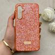 قاب گوشی Galaxy S23 FE سامسونگ نگین دار سواروسکی SWAROVSKI پلاک فلزی نارنجی کد 153036
