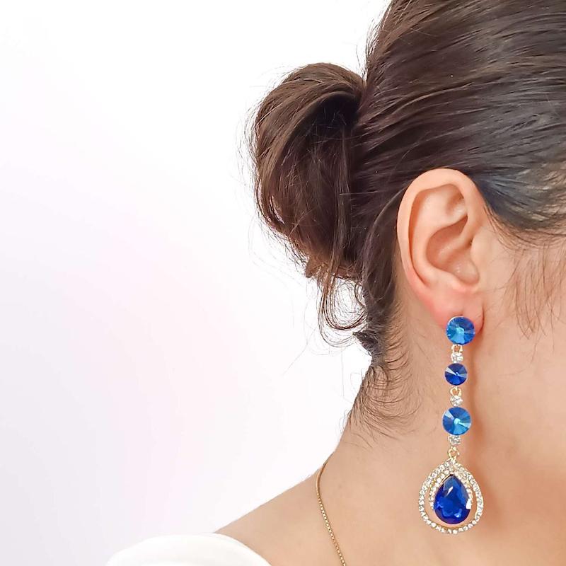 گوشواره آویز اشکی نگین دار زنانه آبی در گوش دختر روبروی دیوار