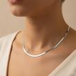 زنجیر هرینگبون نقره‌ای روی گردن مدل با لباس روشن