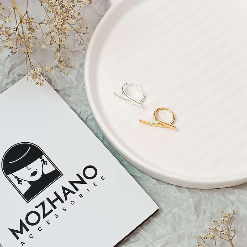 انگشتر طرح خطی روی بشقاب سفید با طراحی مینیمال و رنگ براق طلایی و نقره ای