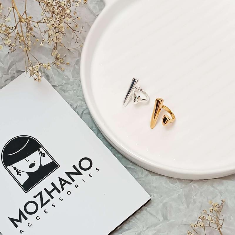 انگشتر استیل طرح خط و نقطه با آبکاری طلا و نقره روی استند سفید کنار کارت Mozhano Accessories