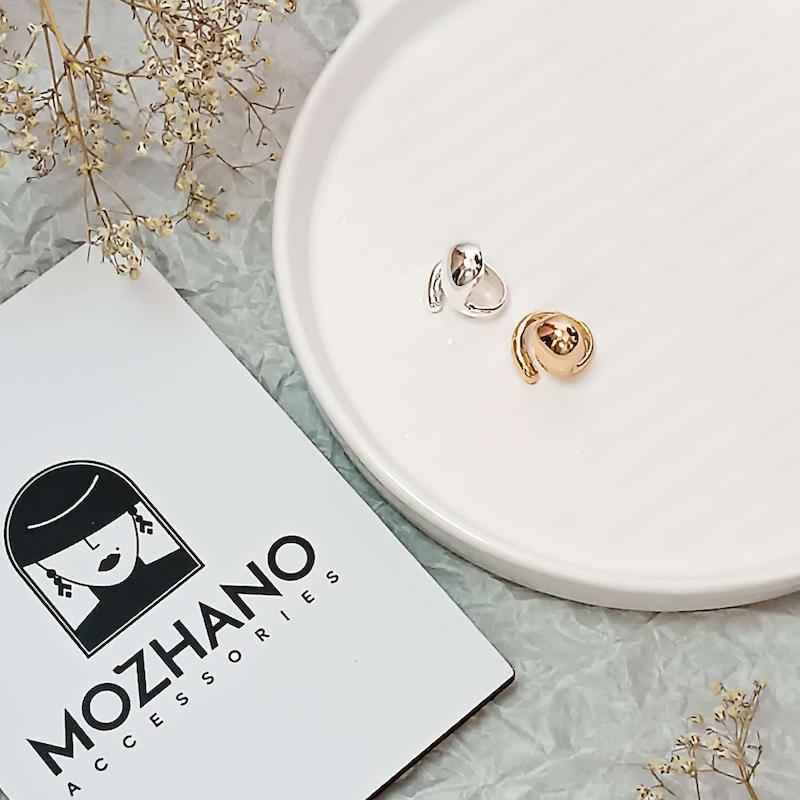 انگشتر طرح دامله دفرمه استیل آبکاری طلایی و نقره روی استند نمایش با لوگوی Mozhano Accessories