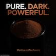 پودر قهوه تازه و تیره آسیاب شده در یک ظرف با پس زمینه مشکی و متن تبلیغاتی «Pure. Dark. Powerful.»