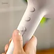 دستی در حال نگه داشتن سشوار فیلیپس مدل BHD500 سفید و فشردن دکمه باد سرد (Cool Shot).