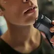نمای نزدیک از فردی در حال اصلاح کامل و نزدیک گردن خود با ریش تراش فیلیپس مدل X3021.