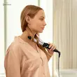 زنی با لباس خواب صورتی در حال فر کردن موهای خود با استفاده از حالت دهنده فیلیپس مدل BHB86400.