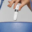 دستی در حال قرار دادن اصلاح موی صورت بانوان براون مدل FS1000 داخل یک کیف دستی آبی رنگ.