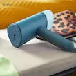 اتو بخارگر فیلیپس مدل STH3000 در حالت تاشده روی مبل در کنار یک کیف پلنگی.