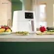 سرخ کن بدون روغن فیلیپس مدل HD9270 سفید روی کانتر آشپزخانه در کنار سبزیجات تازه. 