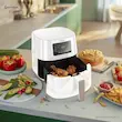 سرخ کن بدون روغن فیلیپس مدل HD9270 سفید با سبد باز حاوی مرغ، در کنار کیک، مافین و سیب‌زمینی.