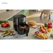 سرخ کن بدون روغن فیلیپس مدل HD9200 روی میز آشپزخانه در کنار انواع غذاهای پخته شده مانند مرغ، سیب‌زمینی و کاپ‌کیک.