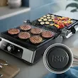 گریل فیلیپس مدل HD6301 در حالت باربیکیو ۱۸۰ درجه که همبرگر و سبزیجات روی آن در حال گریل شدن هستند.