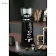 آسیاب قهوه مباشی مدل ME-CG 2300 مشکی روی میز چوبی تیره در کنار پیچر شیر و شیشه دانه قهوه.