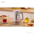 کتری برقی بوش مدل TWK4M221 سفید روی میز در کنار سه فنجان چای مختلف و یک کاسه میوه.