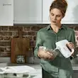 یک زن در حال مخلوط کردن خمیر شکلاتی در کاسه با همزن دستی برقی کنوود مدل HMP30 سفید.