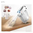 همزن برقی بوش مدل MFQ25200 با چراغ LED Spotlight روشن روی میز چوبی در کنار پاپ کیک.