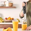 یک دست در حال مخلوط کردن اسموتی میوه ای در لیوان بلند با گوشت کوب برقی براون مدل MQ5275.
