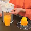 جریان آب پرتقال تازه از دهانه خروجی آب مرکبات گیر براون مدل CJ5050 به داخل لیوان شیشه‌ای.
