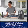 خانم خندان در حال چیدن میز غذا کنار سرخ کن بدون روغن نینجا مدل AF160 در آشپزخانه مدرن.