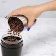 ریختن دانه های قهوه در مخزن استیل آسیاب قهوه دلونگی مدل KG210.