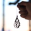 نمای نزدیک از ابعاد واقعی آویز آینه خودرو استیل طرح حسین با تایپوگرافی هنری در دست کاربر