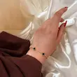 نمای دستبند طلایی ونکلیف گل مشکی روی مچ دست