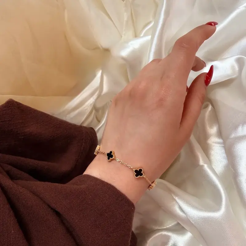 نمای دستبند طلایی ونکلیف گل مشکی روی مچ دست