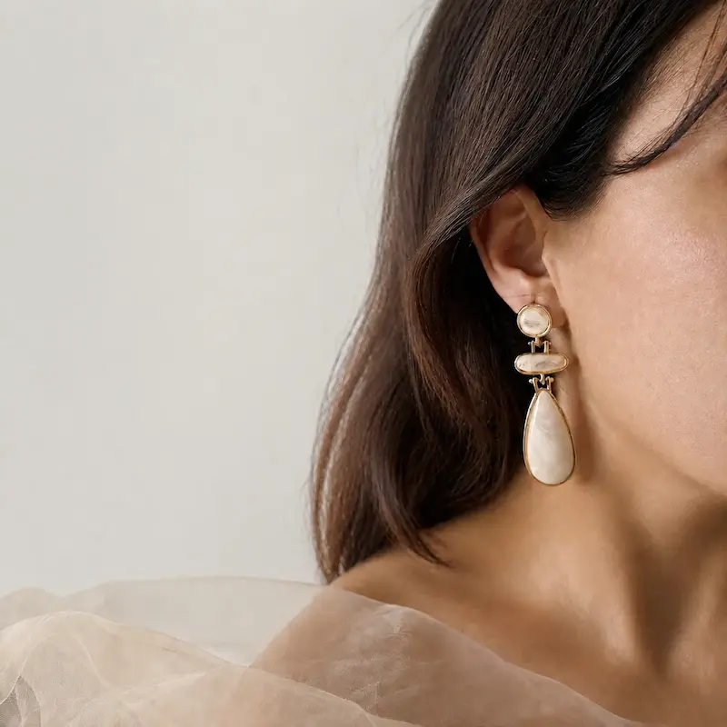 گوشواره آویز بلند سه‌تکه کرم با قاب طلایی و آویز اشکی روی گوش