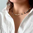گردنبند چوکر مهره ای مشکی با خرج کارهای مکعبی طلایی شیک روی گردن مدل